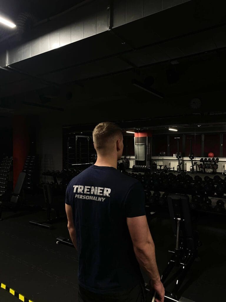 Trener personalny w siłowni – widok z tyłu